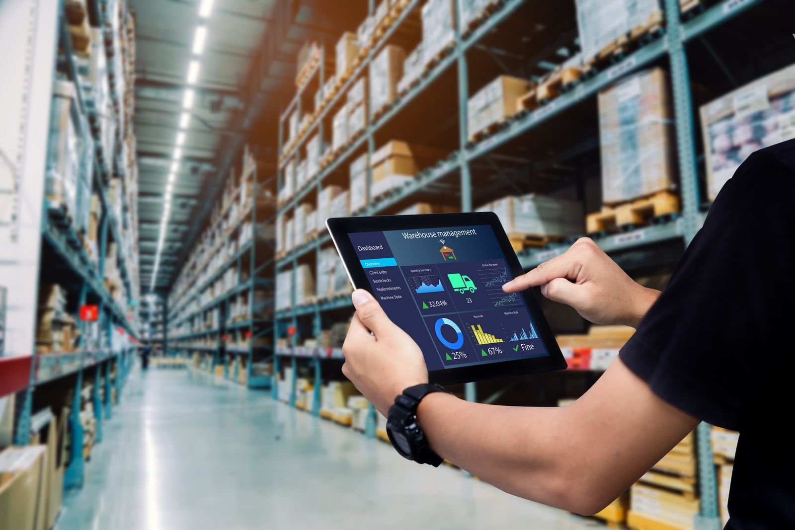Hand touching a tablet while being inside a warehouse